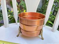 Angled side view showing hammered copper body, brass accent band, and brass feet