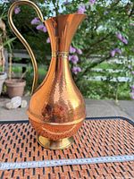 Front profile of hammered copper pitcher showing overall form, brass handle and foot, ruler for scale