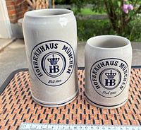 Front view of both steins showing size difference and crest