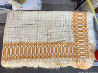 Tablecloth unfolded showing cream weave, mustard geometric border, fringe