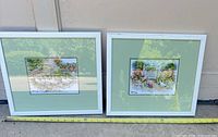 Both framed needlepoint artworks with tape measure showing width