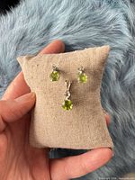 Front view of peridot stud earrings and pendant on fabric cushion