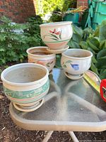Group view of four ceramic pots showing exterior patterns and attached saucers