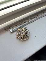 Front view of brooch next to ruler showing size