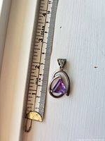 Front view of sterling silver pendant beside ruler showing 1.5 in length