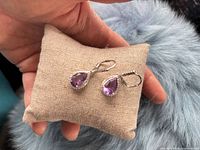 Front view of both amethyst dangle earrings on cushion