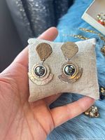 Front view of earrings on cushion showing design and stones
