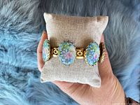 Front view of bracelet on pillow showing porcelain cabochons and gold-tone settings
