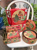 Full set displayed on chair showing boxed packaging, round and rectangular tins