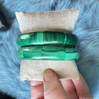 Two stacked green malachite composite bangles on cushion