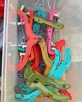 Stack of assorted colour plastic clip hangers inside bin