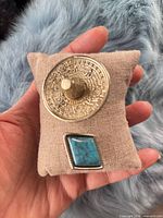 Front view showing round stamped brooch and turquoise clip on cushion