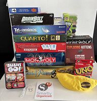 Stacked view showing majority of game boxes, UNO deck, Sushi Go! tin and Bananagrams pouch