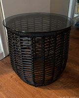 Full view of black synthetic wicker side table with glass top
