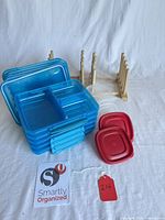 Stacked blue divided containers, red and clear lids, wooden racks visible