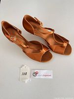 Top view of both bronze satin ballroom dance shoes