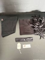 All three accessories laid flat: neck gaiter, scarf with fringe, camo headband