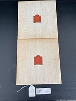 Front covers of both portfolios showing embossed design and red emblem, tag visible