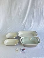Front view of all four cream stoneware dishes and glass lid