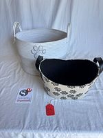 Large white woven rope basket and smaller beige paw print basket side by side