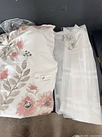 Folded floral shower curtain and white sheer curtain side by side