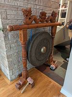 Full view of gong on carved wood stand with mallets
