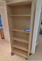 Front view of bookcase showing five shelves and light beige finish