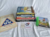 All books laid out showing stack, Oxford International Triathlon booklet, inventory tag, and spiral Run Workouts