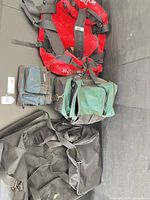 Overview of all four bags laid out: red The North Face duffel, green cooler, blue-black Husky pouch, black duffel