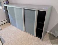 Front view showing silver frame and two frosted glass sliding doors with open shelving at left