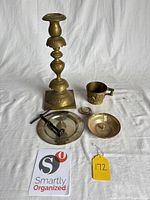 Group view of all brass items: candlestick, cup, dish, lid, clamp piece