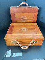 Two stacked wooden briefcases showing exterior, handles, latches, dovetail joints