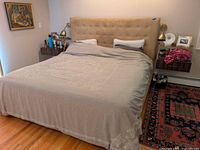 Front view of upholstered headboard installed behind queen bed showing button-tufting and overall style