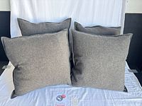 Front view of four gray charcoal square pillows