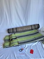 Rolled woven rug and stacked striped curtain panels on white background