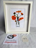Front view showing framed botanical photograph with orange poppies in glass bottle, white frame, mat