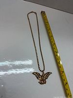 Full view of necklace beside tape showing 18 in chain and eagle pendant