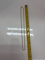 Full view of necklace beside measuring tape showing 18 in length