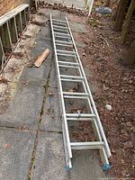 Full view of collapsed aluminum extension ladder on ground