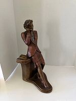 Front angled view of full figurine showing woman leaning on desk