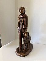 Front view of bronze-tone sculpture showing woman and dog