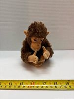 Front view of brown plush monkey measuring about 16 cm