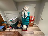 Overall lot showing stacked teal totes, boxed tree, plush elves on top, various bins