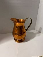 Front view of polished copper and brass pitcher