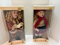 Two boxed 18" Cracker Barrel caroling dolls side by side