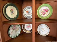 Six decorative plates displayed in cabinet