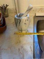 Mortar and pestle beside measuring tape showing width