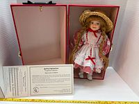 Doll inside red presentation box with certificate visible