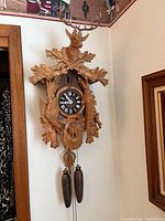 Front view showing full carved wood cuckoo clock with weights