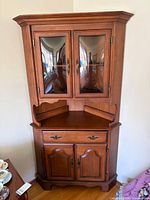 Full view of Krug corner hutch showing glass-door top, drawer, and paneled base